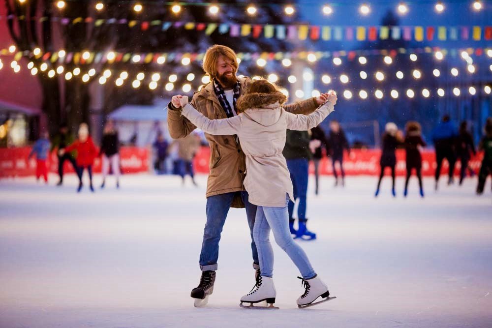 Couple skating on ice at Canary Wharf Winter Lights 2025. Couple ice skating at Canary Wharf Winter Lights 2025 ice rink