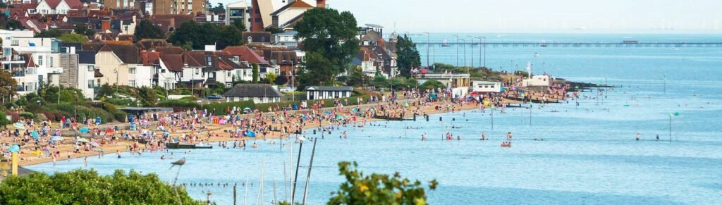 A peaceful view of Chalkwell Beach in Essex, with soft sand, calm blue water, and families enjoying a relaxing day by the sea